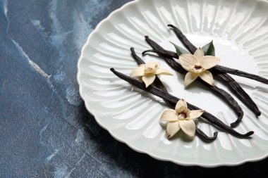 Aromatik vanilyalı tabaklar ve mavi arka planda çiçekler.