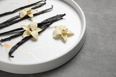 Aromatik vanilyalı tabaklar ve gri arka planda çiçekler.