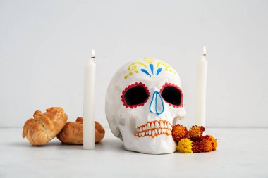 Mumlarla, çiçeklerle ve beyaz arka planda boyanmış kafatasıyla ölülerin ekmeği. Meksika Ölüler Günü 'nün Kutlaması (El Dia de Muertos)