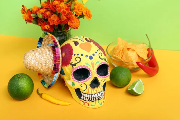 Mexican skull with marigold flowers and lime on yellow table against green background. Mexico\'s Independence Day celebration