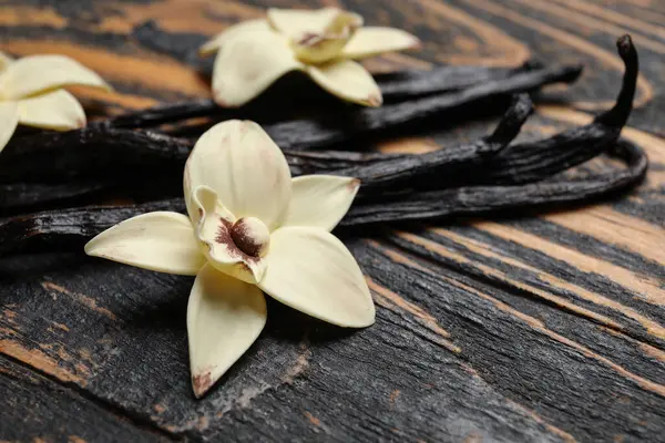 Siyah Ahşap Arka Planda Aromatik Vanilya Çubukları Çiçekler — Stok fotoğraf