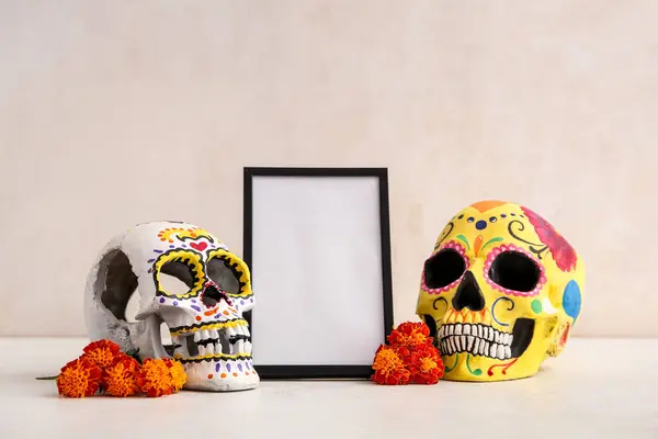 Frame with marigold flowers and painted skulls on white table. Celebration of Mexico\'s Day of the Dead (El Dia de Muertos)