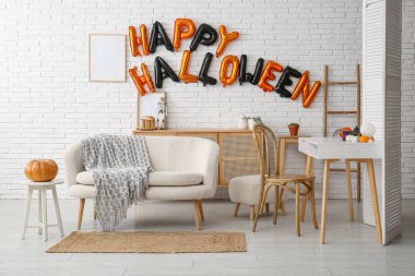 Cadılar Bayramı için dekore edilmiş oturma odasının içinde balonlar, masa ve kanepe var.