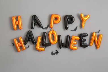 Balonlardan ve gri duvarda asılı kağıt yarasalardan yapılmış Cadılar Bayramınız kutlu olsun.