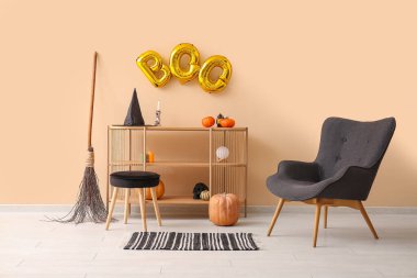 Rafa kaldırma ünitesi, koltuk ve balonlardan yapılmış mesaj BOO oturma odasındaki bej duvarda asılı.