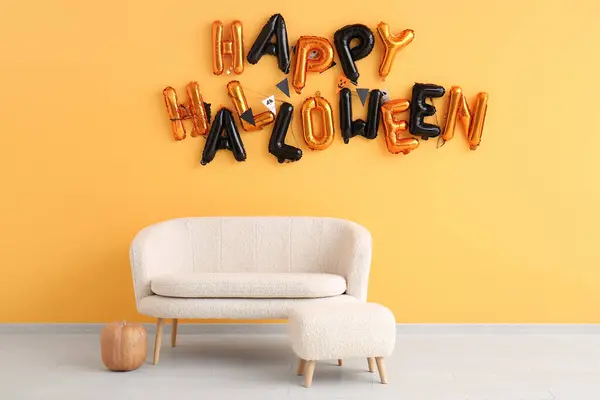 Sofa, bench and text HAPPY HALLOWEEN made of balloons hanging on orange wall in living room