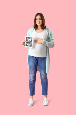 Pembe arka planda sonogram görüntüsü olan hamile bir kadın.