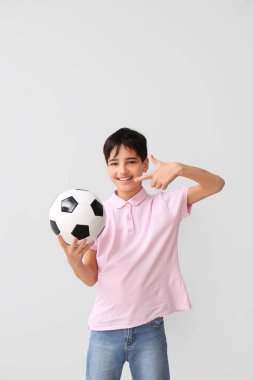 Gri arka planda futbol topu olan küçük çocuk.