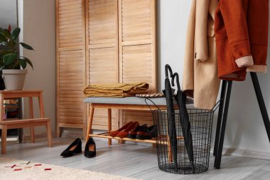 Ayakkabılı bankta, şemsiyeli ve koridordaki raflarda asılı giysiler.