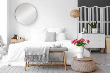 Hafif yatak odasının içinde yumuşak bir bank ve vazoda laleler.