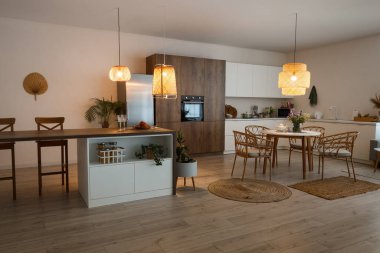 Modern mutfak, yemek masası, ada ve parlayan lambalar.