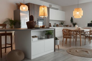 Modern mutfak, yemek masası, ada ve parlayan lambalar.