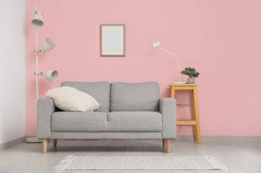 Oturma odasının içinde, pembe duvarın yanında kanepe var.