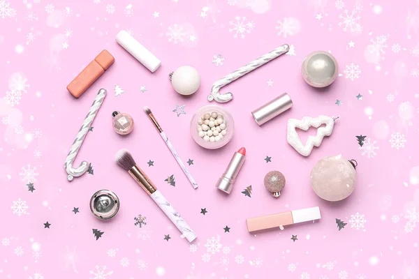 Makeup products with Christmas decor on pink background