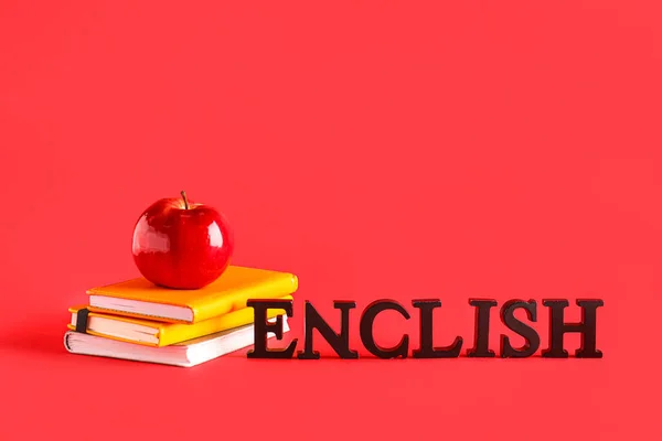 Books with fresh apple and word ENGLISH on red background