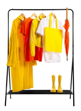 Beyaz arka planda şık kıyafetler ve lastik çizmelerle dizilin.