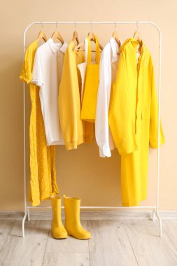 Renkli duvarın yanında şık kıyafetler ve lastik çizmelerle dizilin.