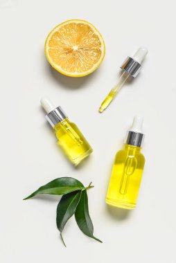 Hafif arka planda bitkiler bulunan limon yağı şişeleri.