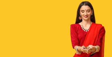 Güzel Hintli kadın sarı arka planda diya lambası tutuyor, mesaj için yeri var. Diwali kutlaması