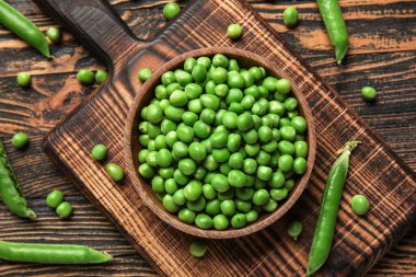 Tahta zemin üzerinde taze bezelyeler olan bir kase ve yemek.