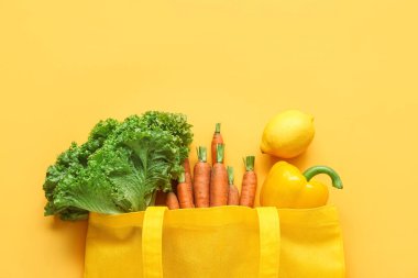 Bej arka planda farklı taze sebzelerle eko poşeti.