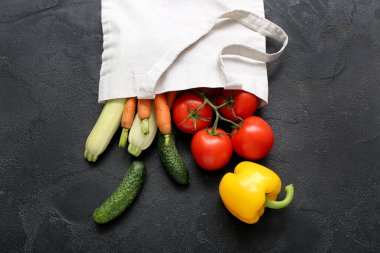 Siyah arka planda farklı taze sebzelerin bulunduğu bir poşet.