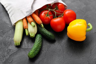 Siyah arka planda farklı taze sebzeler olan çevre torbası, yakın plan.