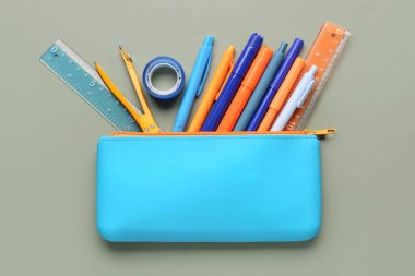 Yeşil arka planda okul kırtasiyesi olan mavi kalem çantası.