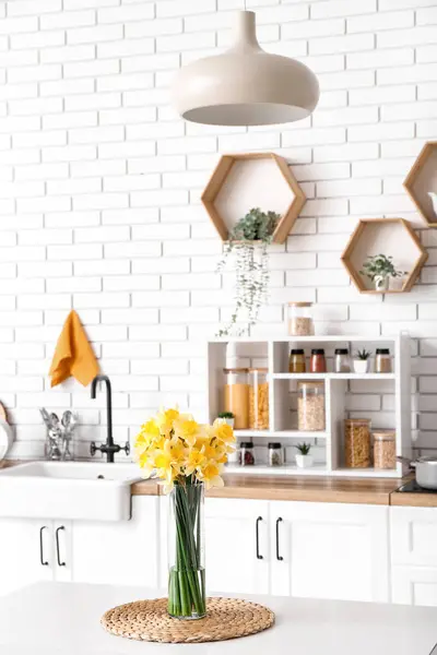 Mutfağın içindeki masada çiçek açan vazo.