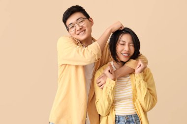 Genç Asyalı arkadaşlar bej arka planda sarılıyorlar