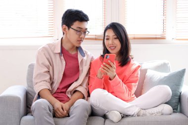 Evde cep telefonu kullanan Asyalı genç arkadaşlar