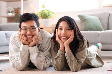 Genç Asyalı arkadaşlar evde yerde yatıyorlar.