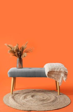 Turuncu arka planda yumuşak bankta otlu vazolar.