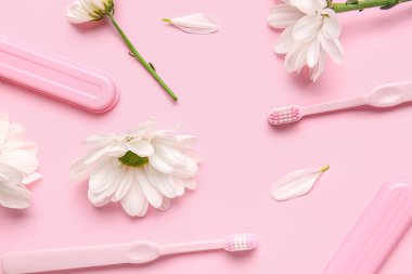 Pembe arka planda diş fırçaları, davalar ve papatya çiçekli kompozisyon