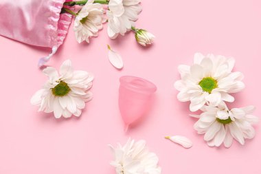 Adet bardağı ve pembe arka planda güzel papatya çiçekleri olan kompozisyon