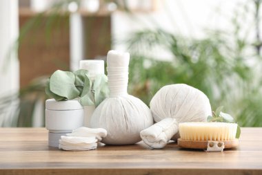 Spa aksesuarları, kozmetik ürünleri ve okaliptüs dallarıyla ahşap masa üzerinde kompozisyon