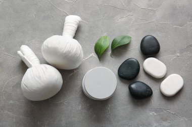 Bitkisel masaj torbaları, spa taşları ve grunge arkaplanda kozmetik ürünler içeren kompozisyon