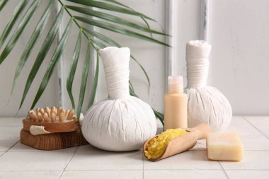 Hafif arka planda kaplıca aksesuarları, kozmetik ürünleri ve palmiye yaprağı