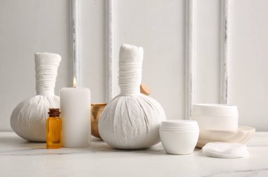 Spa aksesuarları, kozmetik ürünleri ve ışık arka planında yanan mum bileşimi