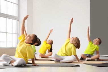 Beden dersinde yoga yapan bir grup çocuk.