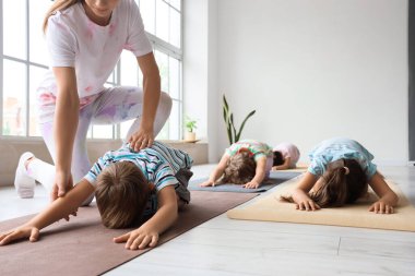 Beden eğitimi hocasıyla yoga yapan bir grup çocuk.