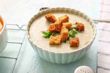 Beyaz arka planda kızarmış ekmeklerle bir kase lezzetli krema çorbası.