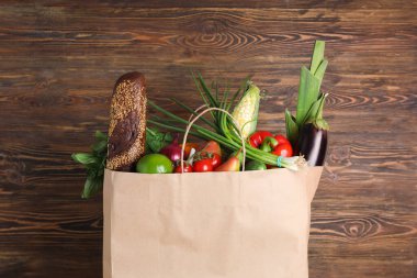 Tahta zemin üzerinde farklı ürünler olan kağıt torba.