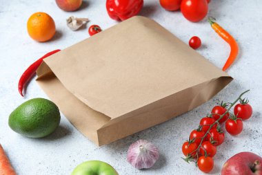 Kese kağıdı ve açık mavi arka planda sebzeli meyveler.