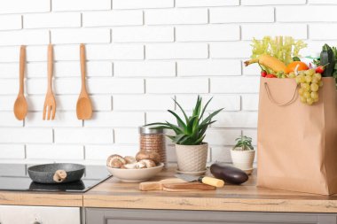 Mutfak tezgahında farklı ürünler ve çatal bıçaklarla dolu kağıt torba.