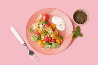 Pembe arka planda peynirli, fesleğenli ve ekşi kremalı kaynamış hamur köftesi tabağı.