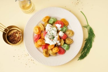 Ekşi kremalı ve dereotlu kaynamış renkli hamur tatlısı tabağı.