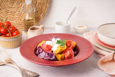 Beyaz arka planda ekşi kremalı ve maydanozlu kaynamış renkli hamur köfteleri.