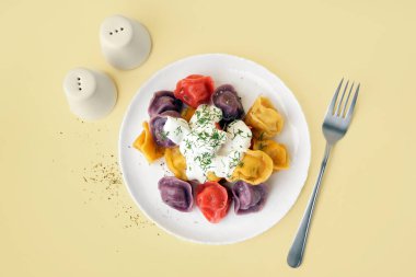 Ekşi kremalı ve dereotlu kaynamış renkli hamur tatlısı tabağı.