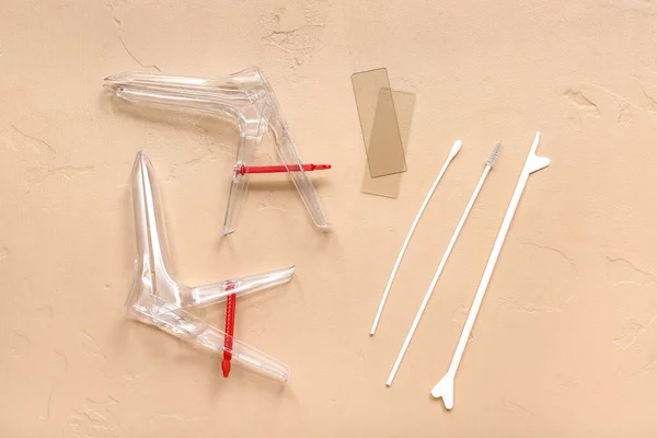 Gynecological speculums and pap smear test tools on beige background